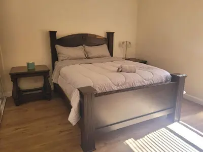 a bedroom with a bed with a wooden headboard and two tables at 3BR & Loft near Palmdale Hospital in Palmdale