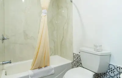 a bathroom with a shower curtain and a toilet at Colonial Palace Inn in Downey