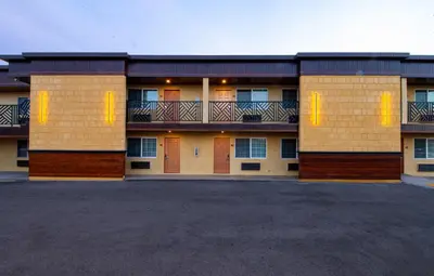 a large building with orange doors and a parking lot at Colonial Palace Inn in Downey