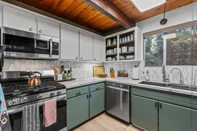 a kitchen with white cabinets and a stove top oven at Fleming Creek Hideaway, Next to Creek, Fire-Pit! in Lake Arrowhead