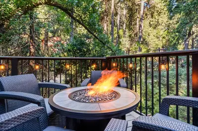 a fire pit sitting on a deck with chairs at Fleming Creek Hideaway, Next to Creek, Fire-Pit! in Lake Arrowhead
