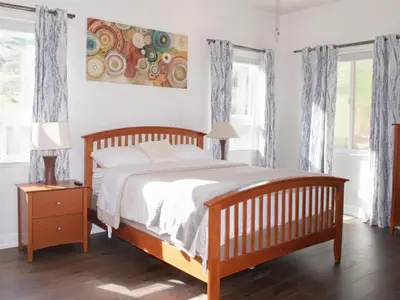 a bedroom with a wooden bed and two windows at 3BR Mountain Retreat with 2 Executive Suites & Scenic Views Sleeps 6 in Newbury Park