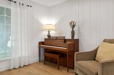 a piano in a living room with a chair and a lamp at 1970s Style Cozy Home with Fireplace Yard and Hot Tub in Inglewood