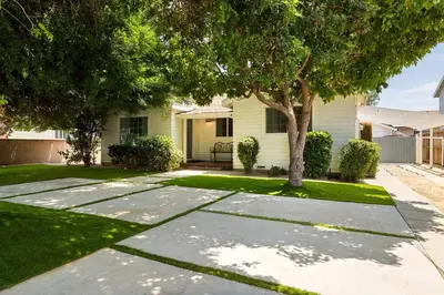 a house with a tree in the yard at 1970s Style Cozy Home with Fireplace Yard and Hot Tub in Inglewood