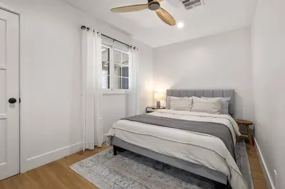 a white bedroom with a bed and a ceiling fan at 1970s Style Cozy Home with Fireplace Yard and Hot Tub in Inglewood
