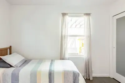 a bedroom with a bed with a striped blanket and a window at Perfect Venice Beach Vacation Home for Couples and Families in Los Angeles