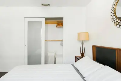 a white bedroom with a bed and a mirror at Perfect Venice Beach Vacation Home for Couples and Families in Los Angeles