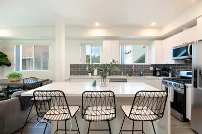 a kitchen with a large white island with four chairs at La Veranda View Hideaway in Los Angeles