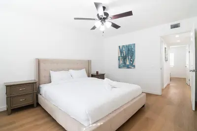 a white bedroom with a bed and a ceiling fan at 2BR Plus Bonus Room and Pool Access Near Universal Studios in Los Angeles