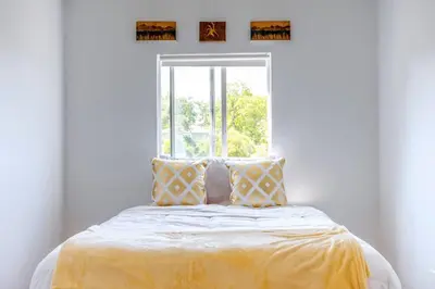 a bed with a yellow blanket and a window at Sunset Hilltop Flat in Los Angeles