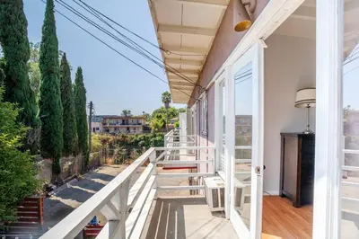 a white house with a balcony with trees at Sunset Hilltop Flat in Los Angeles