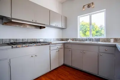 a kitchen with white cabinets and a window at Sunset Hilltop Flat in Los Angeles