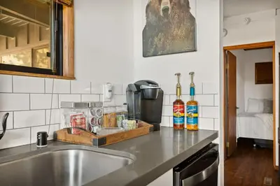 a kitchen with a sink and a counter top with bottles of alcohol at YOLO Lake Escape in Big Bear Lake