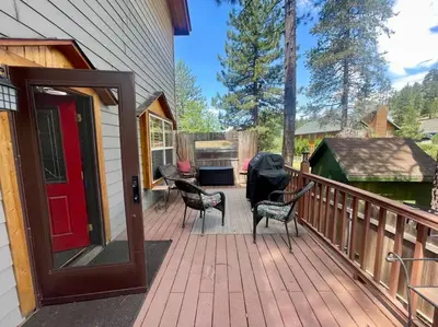 a wooden deck with chairs and a red door at Cabin 7 sleeps 8 BEAUTIFUL BOULDER BAY, BIG BEAR in Big Bear Lake