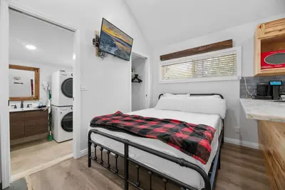a small bedroom with a bed and a kitchen at Little Lux - Hot Tub, Walk to Village & Lake in Big Bear Lake