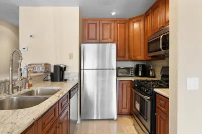 a stainless steel refrigerator in a kitchen with wooden cabinets at Lakeview Condo - Lakefront Complex, Lake Views, Heated Pool in Big Bear Lake