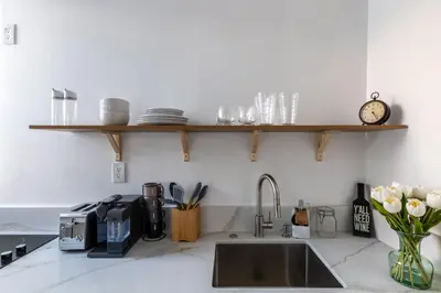 a kitchen counter with a sink and a clock on a shelf at Walking distance to Caltech convention Center Pasadena Landmark room in Pasadena