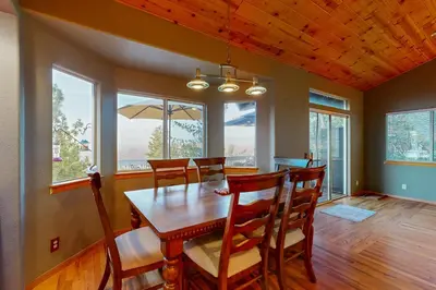 a dining room with a table and chairs and windows at Cloud Nine in Lake Arrowhead
