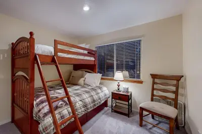 a bedroom with two bunk beds and a chair at Cloud Nine in Lake Arrowhead
