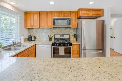 a kitchen with wooden cabinets and stainless steel appliances at Spacious House, Central, All Amenities in Harbor City