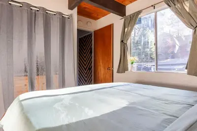 a bedroom with a large bed with a window at Beautiful A-Frame Mountain Cabin with Hot Tub! in Running Springs