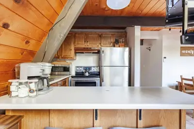 a kitchen with wooden cabinets and a stainless steel refrigerator at Beautiful A-Frame Mountain Cabin with Hot Tub! in Running Springs