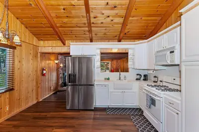 a kitchen with white cabinets and a stainless steel refrigerator at Village Hideaway walking to the village in Big Bear Lake