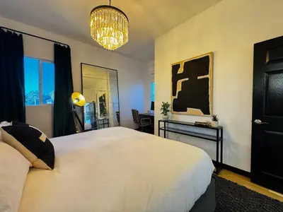 a bedroom with a large white bed and a chandelier at The Loft at Butler in Los Angeles