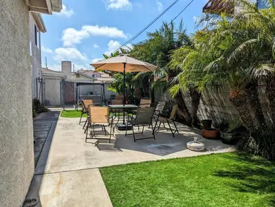a patio with a table and chairs and an umbrella at 5 Minutes to South Bay Beaches! Private 2 bedroom 2 bath 2 level home with patio Excellent value! in Torrance