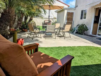a backyard with chairs and an umbrella and grass at 5 Minutes to South Bay Beaches! Private 2 bedroom 2 bath 2 level home with patio Excellent value! in Torrance