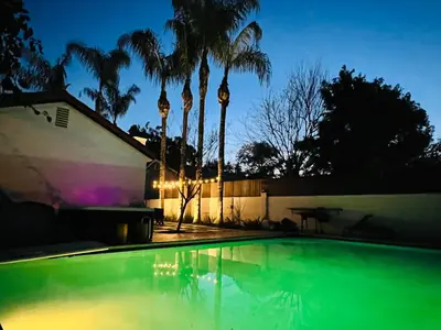 a swimming pool in front of a house with palm trees at Mediterranean Villa-Pool Jacuzzi BBQ-Malibu Bliss in Los Angeles