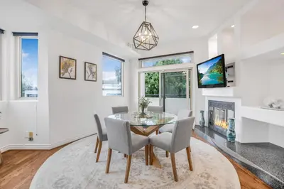 a dining room with a glass table and chairs and a fireplace at Franklin Mediterranean Villa in Los Angeles