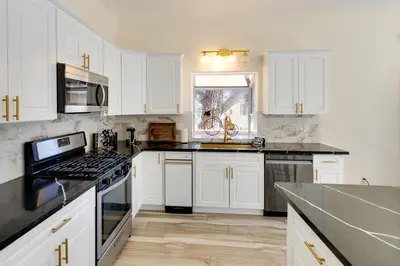 a kitchen with white cabinets and black counter tops at Game Room and Deck Modern Frazier Park Home! in Pine Mountain Club