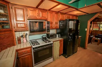 a kitchen with wooden cabinets and a black refrigerator at A Big Olympic Getaway in Big Bear Lake