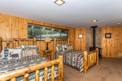 two beds in a room with wooden walls at Big Bear Splash in Big Bear Lake