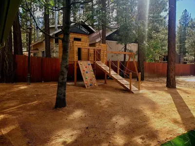a tree house with a playground in the woods at Big Bear Splash in Big Bear Lake