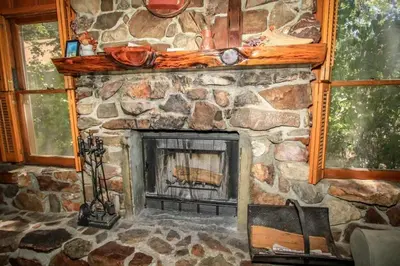 a stone fireplace in a room with two windows at Mountain Air in Big Bear Lake