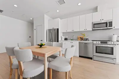 a kitchen with white cabinets and a wooden table and chairs at Stylish LA Getaway near Downtown - Prime Location on Wilshire Blvd! in Los Angeles