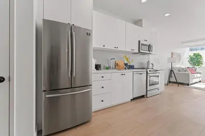 a kitchen with a stainless steel refrigerator and white cabinets at Modern Retreat in Koreatown - Perfect for Your LA Stay! in Los Angeles