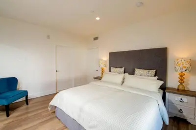 a bedroom with a white bed and a blue chair at New Modern 3BR 3BA Apt in Central Los Angeles with Rooftop & Parking in Los Angeles