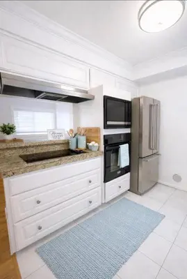 a kitchen with white cabinets and stainless steel appliances at Beachside Gem, Steps to Pier in Manhattan Beach