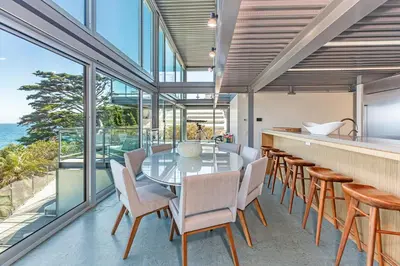 an open kitchen and dining room with a glass table and chairs at Beachfront Villa Broad Beach Direct Beach Access in Malibu