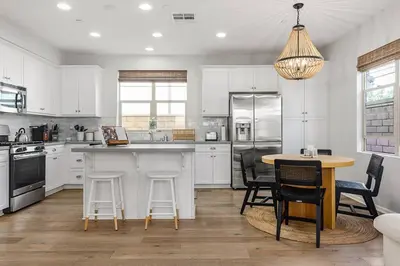 a kitchen with white cabinets and a table and chairs at GOODE HOMES Luxury Villa with Community Pool and Spa in Santa Clarita