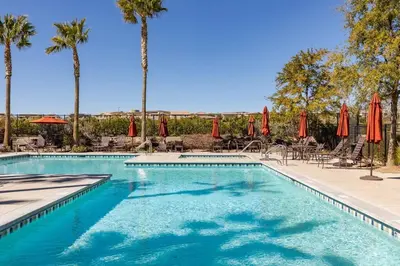 a pool with umbrellas and chairs and palm trees at GOODE HOMES Luxury Villa with Community Pool and Spa in Santa Clarita