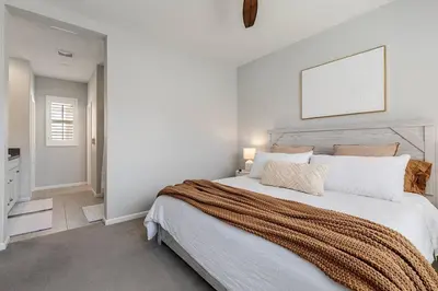a white bedroom with a large bed with a wooden headboard at GOODE HOMES Luxury Villa with Community Pool and Spa in Santa Clarita