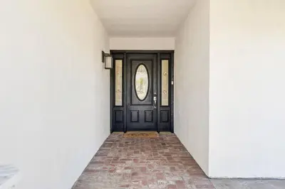 an empty hallway with a black door with a window at GOODE HOMES Cozy 4 Bedroom Home with Jacuzzi in Santa Clarita