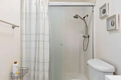 a white bathroom with a shower curtain and a toilet at GOODE HOMES Cozy 4 Bedroom Home with Jacuzzi in Santa Clarita