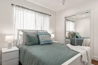 a bedroom with a bed with blue pillows and a mirror at Goode Homes Luxury Family Home in Granada Hills