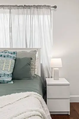 a bedroom with a bed with a night stand and a lamp at Goode Homes Luxury Family Home in Granada Hills