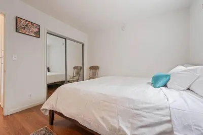 a bedroom with a white bed with a blue pillow on it at Sawtelle Serenity- Modern Comfort in Los Angeles